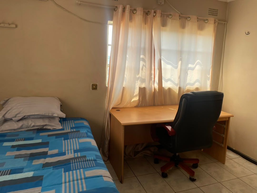 Room with a blue patterned bedspread and a wall-mounted air conditioner