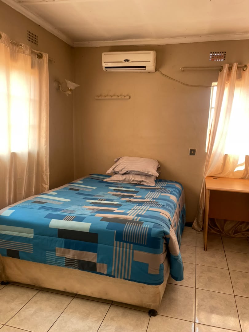 Large bed with a grey throw, blue curtains and a patterned rug