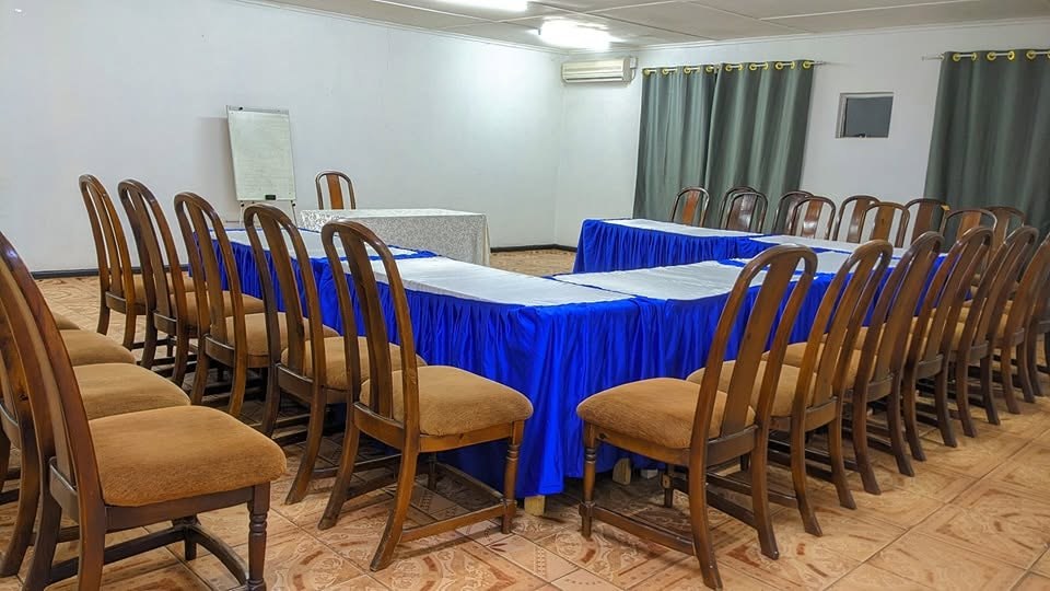 Conference hall with blue-draped tables, a flip chart and a wall-mounted air conditioner