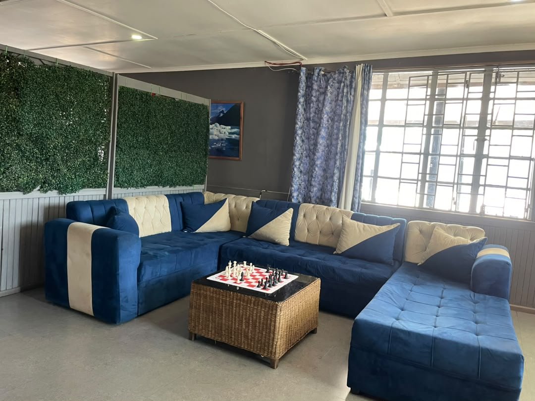 Blue sofa lounge with a chess board on a wicker table, a green leaf wall and a large window